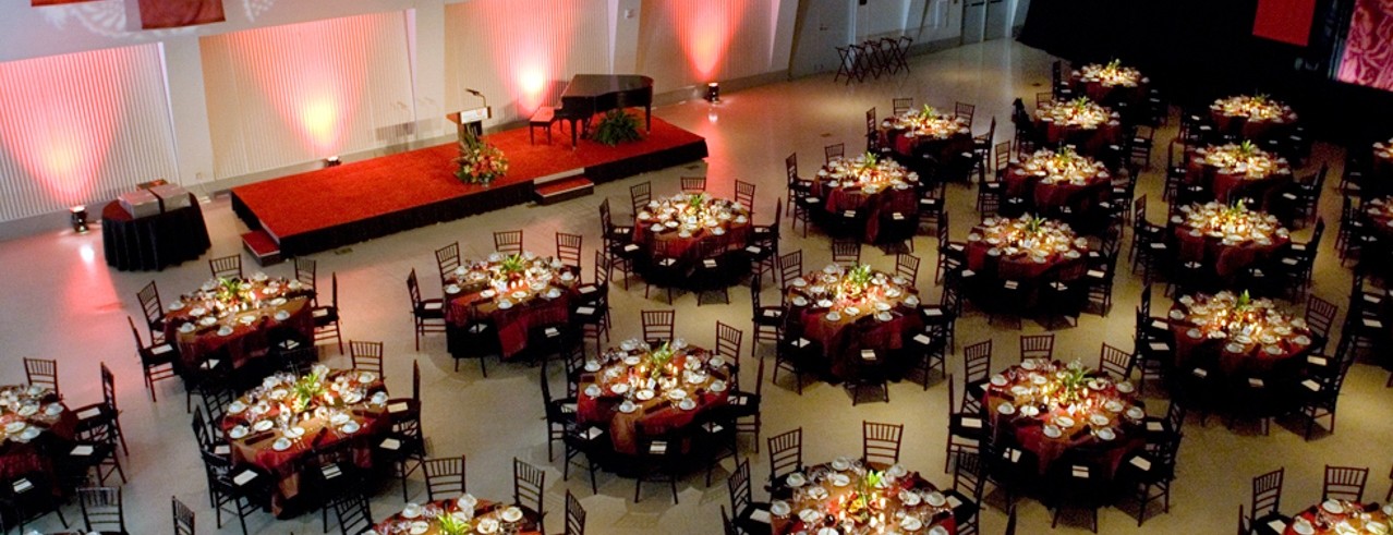 Round tables with formal dinner settings and chairs in Tangemann University Center Great Hall.