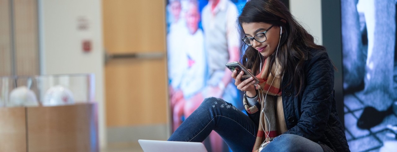 a student working on her laptop with a classroom in the background