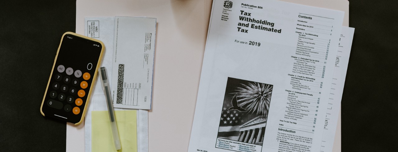 Tax forms and a calculator lay on a manila folder.