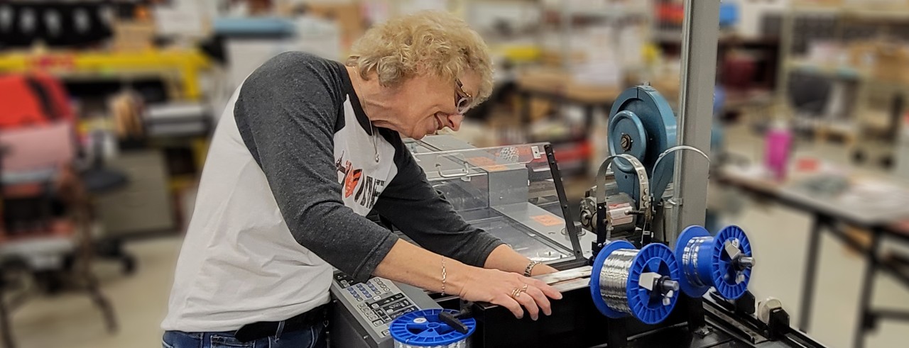 Female printing employee sets machine for stitching