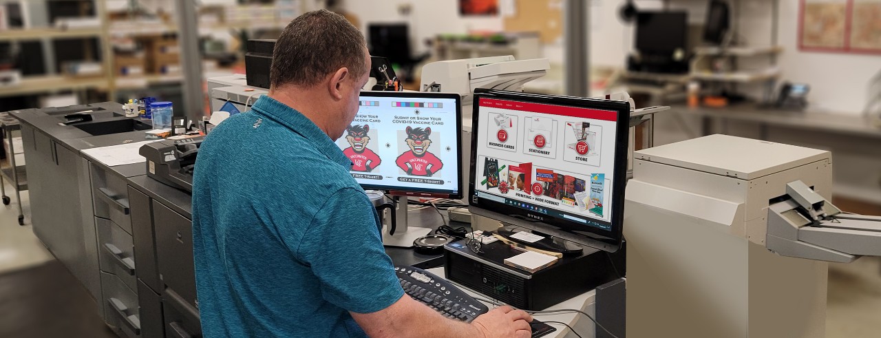 Printing operator stands at computer preparing file