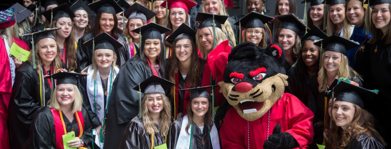 The Bearcat poses in his graduation cap and gown with other students at graduation.