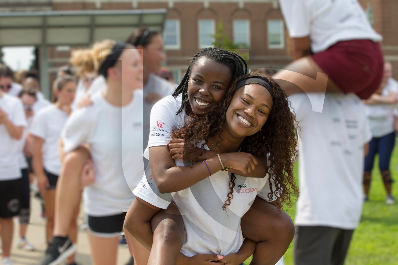 A student smiles as she gives another student a piggy-back ride