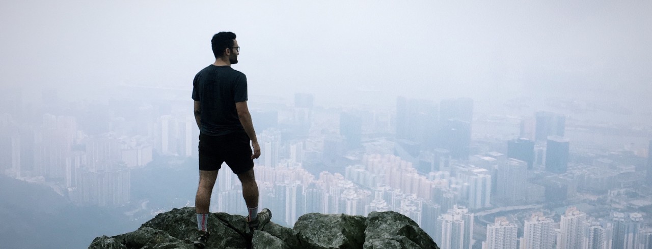Student stands above the Hong Kong skyline in fog.