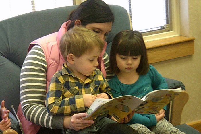 A volunteer in a rocking chair reads to toddlers