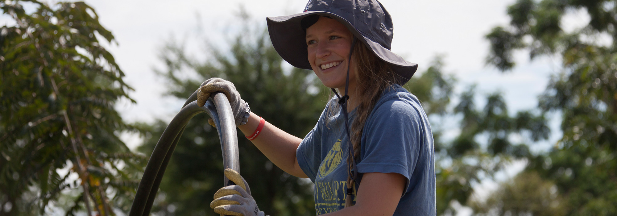 Engineering student Ashley Mosher roles water pipe along a road in Tanzania