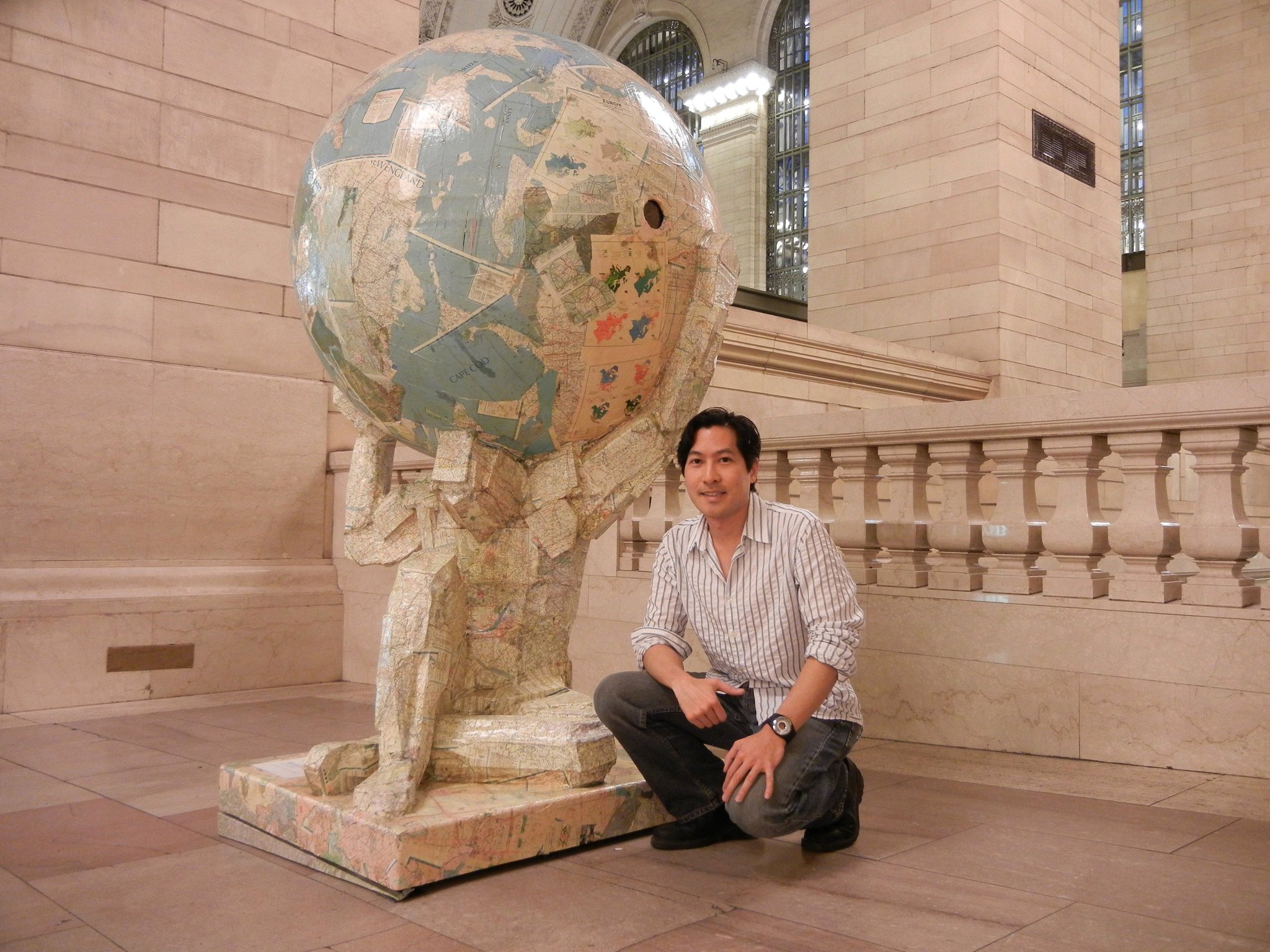 Picture of tom tsuchiya kneeling next to Atlas Sculpture