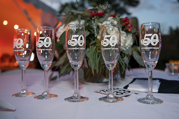 Line of Champagne glasses etched with a UC Clermont's 50 year celebratory mark to commemorate college and celebration