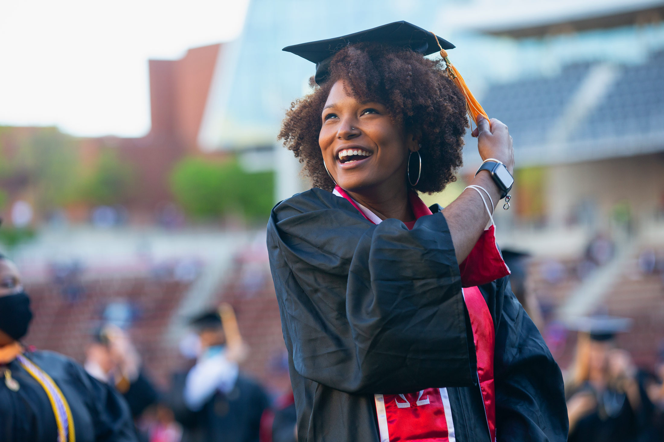 A University of Cincinnati grad smiles as she adjusts her tassel