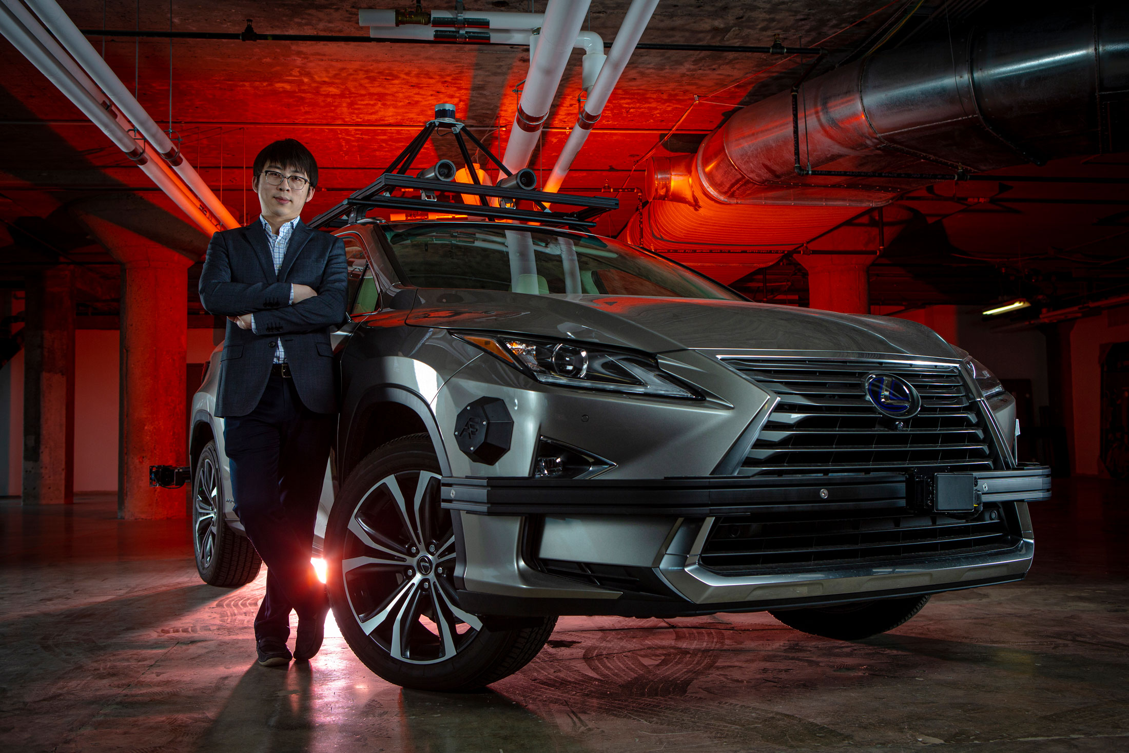 A UC Professor stands beside a self-driving car