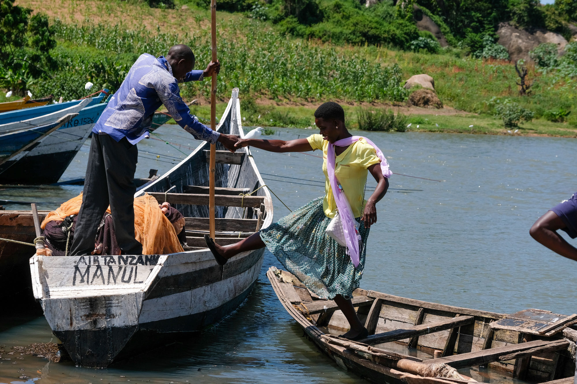 Man helps woman onto a small boat in Tanzania