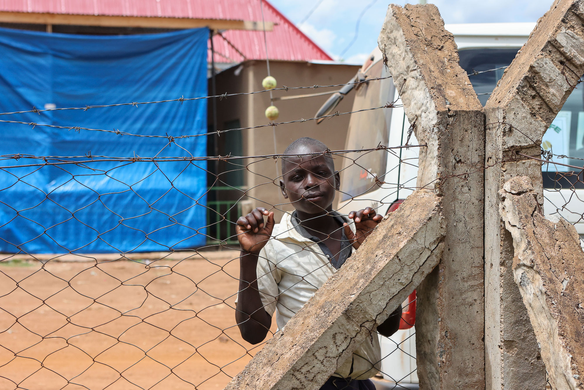 Tanzanian child looks at camera from behind wire fence