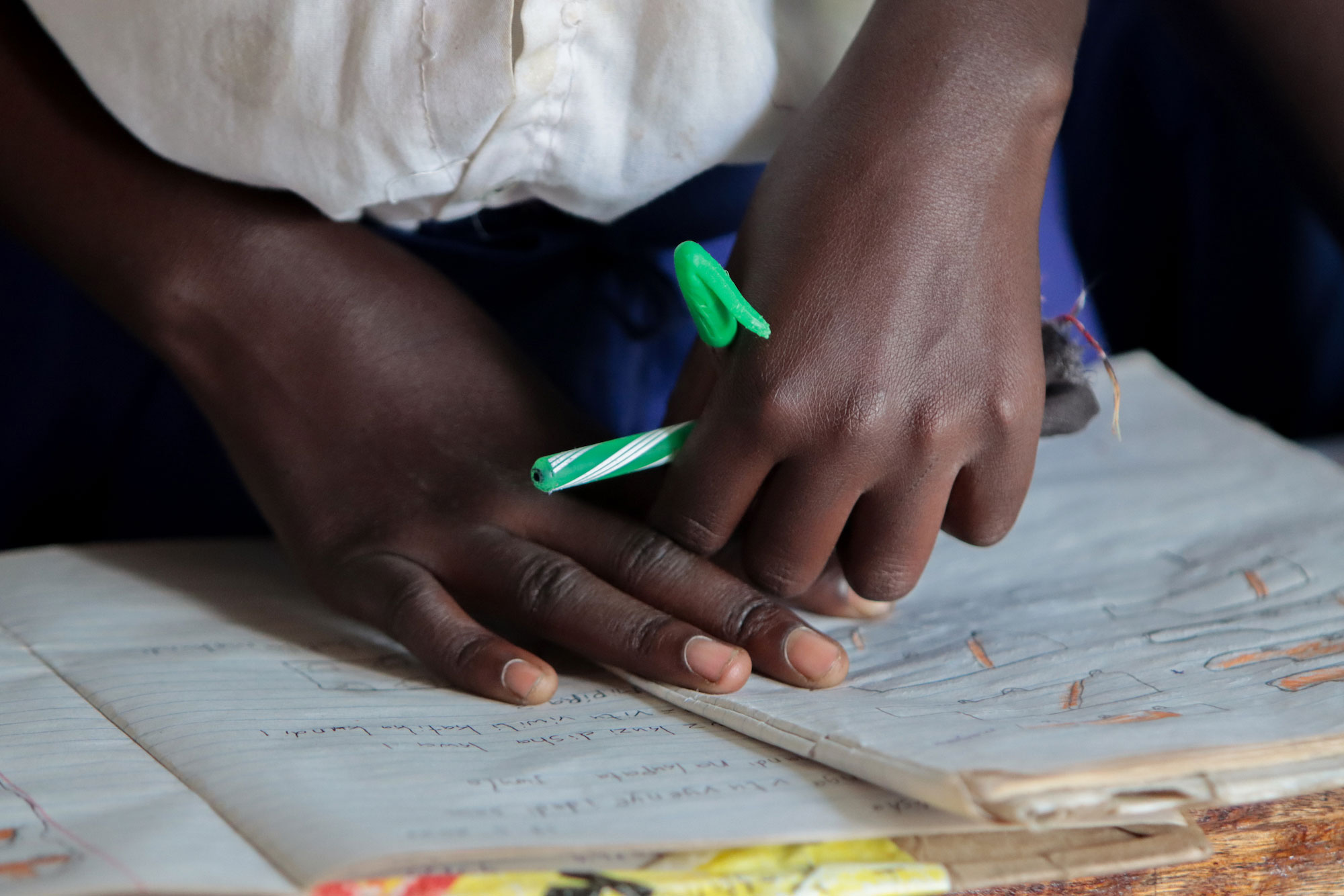 Close-up of child's hand with pen and notebook paper