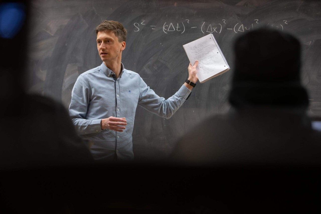 a man standing in front of a blackboard leading a discussion 