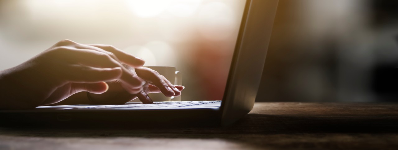 Two hands rest over a laptop keyboard, ready to start typing. 