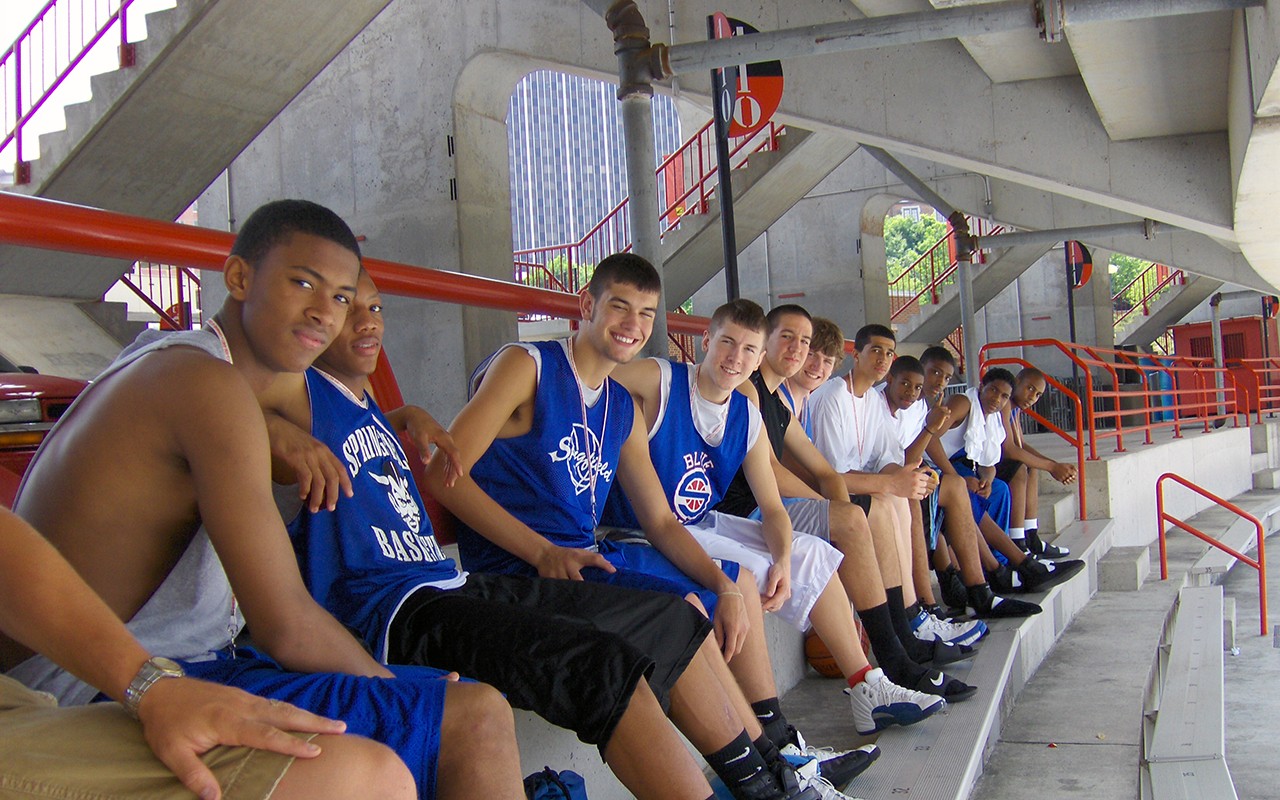 Ten teen basketball players seated in Nippert Stadium during a camp break.