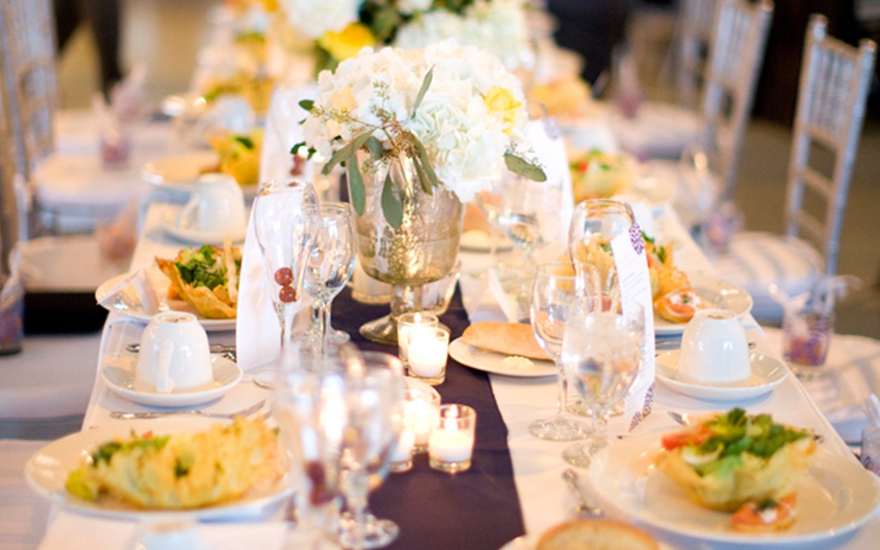 Catered meal for wedding on decorated rectangular banquet table.