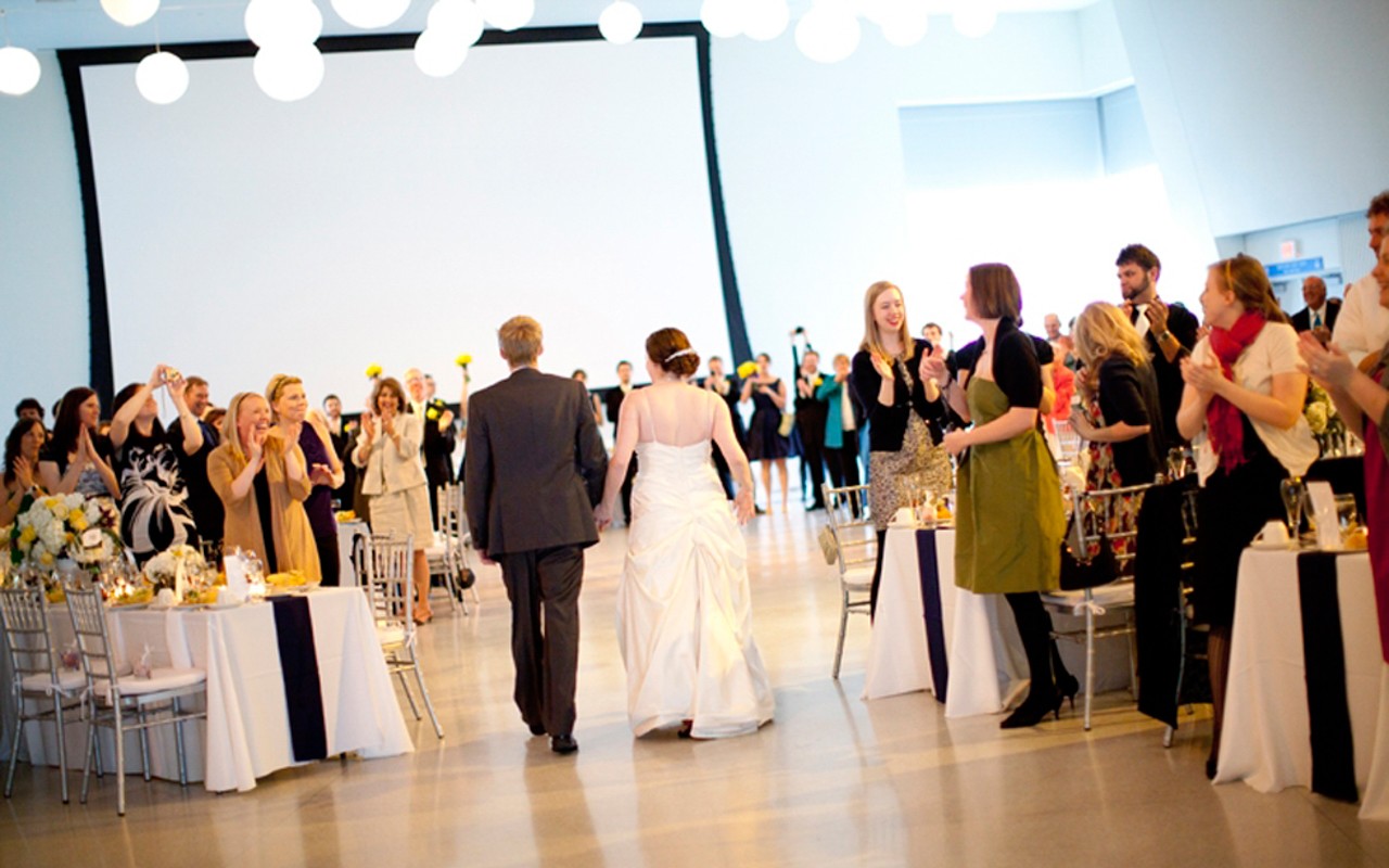 Bridal couple make their grand entrance in Great Hall with guests applauding.