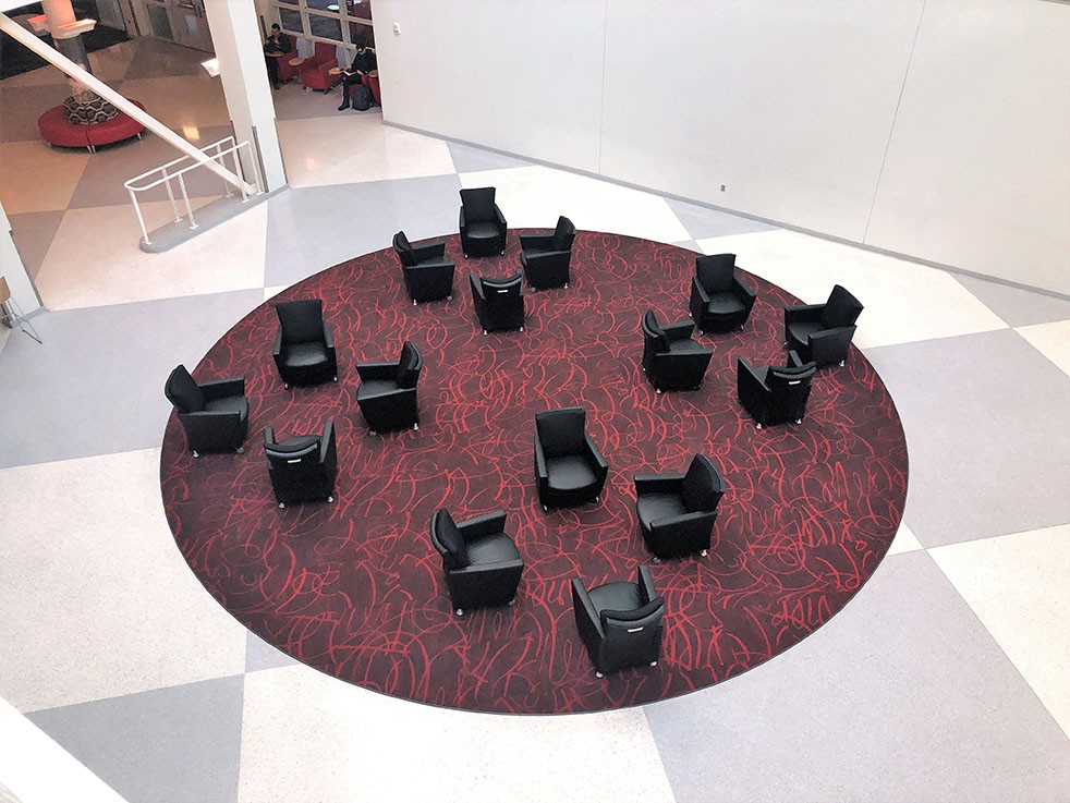 Overhead view of circular rug on tile floor with lounge chairs.