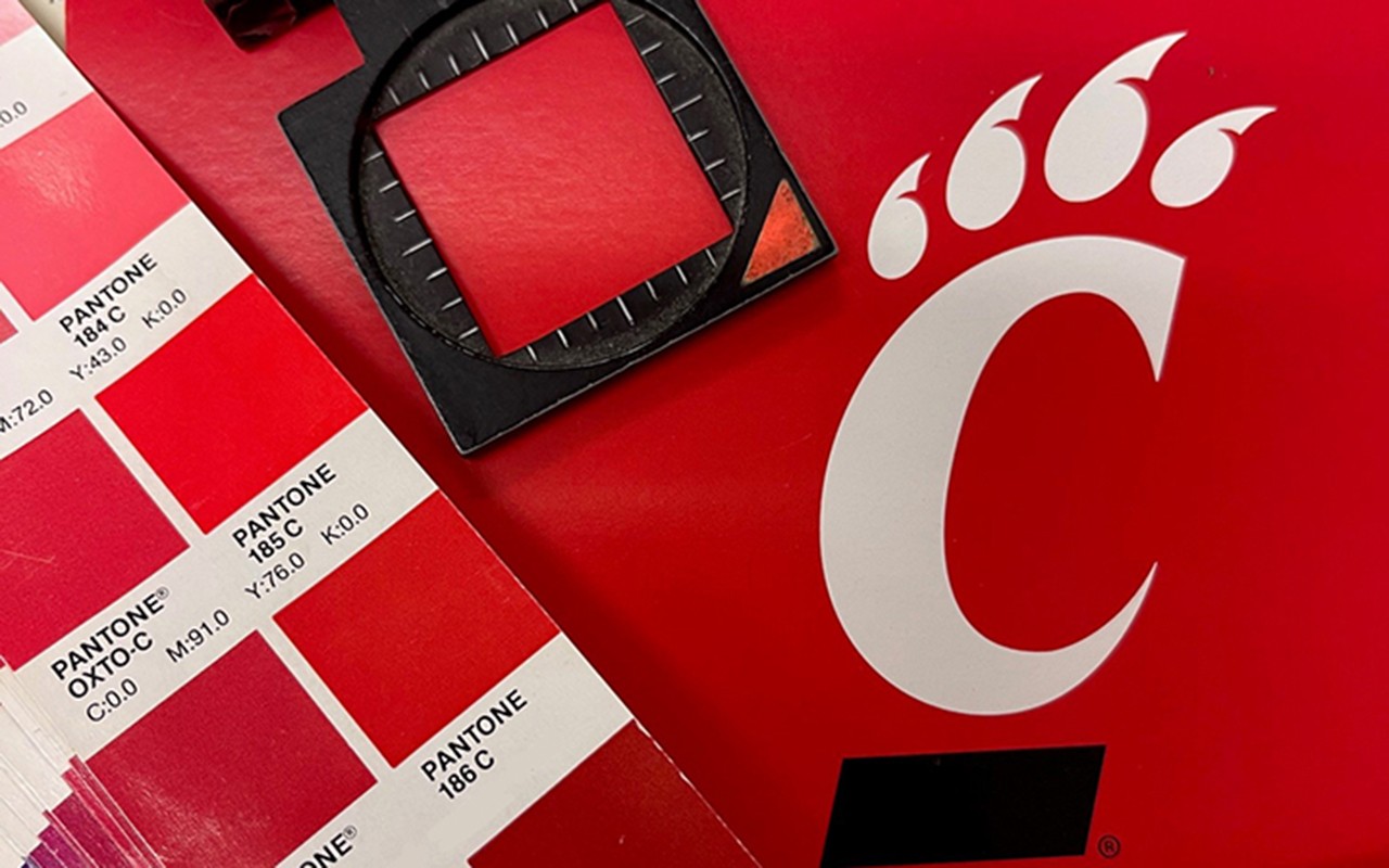 A Pantone color book sits on a printed athletic logo to check the color is correct