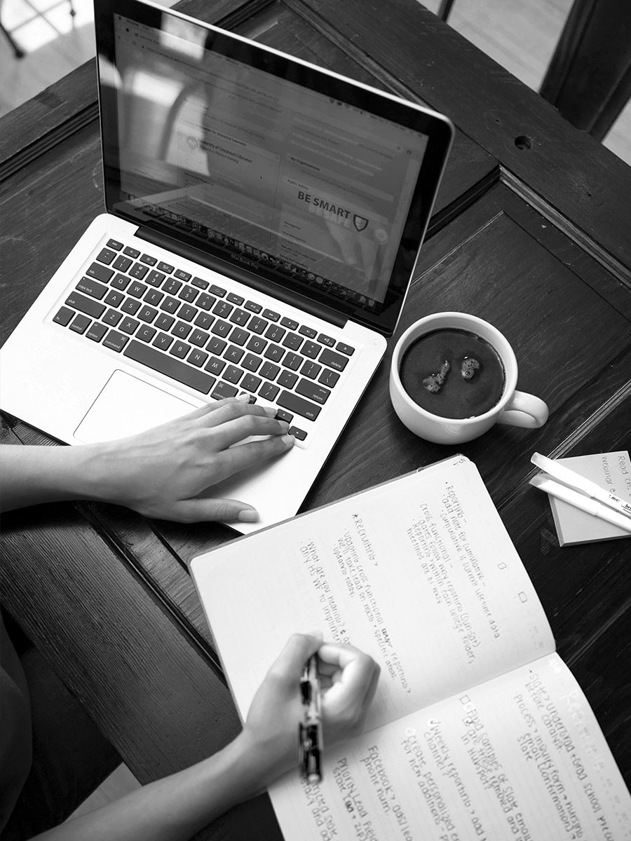 Student using computer and writing in notebook