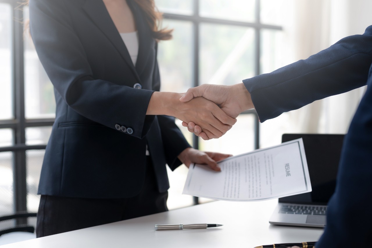 Professional man and woman shaking hands, faces out of view - Sociology major using degree  to land a job