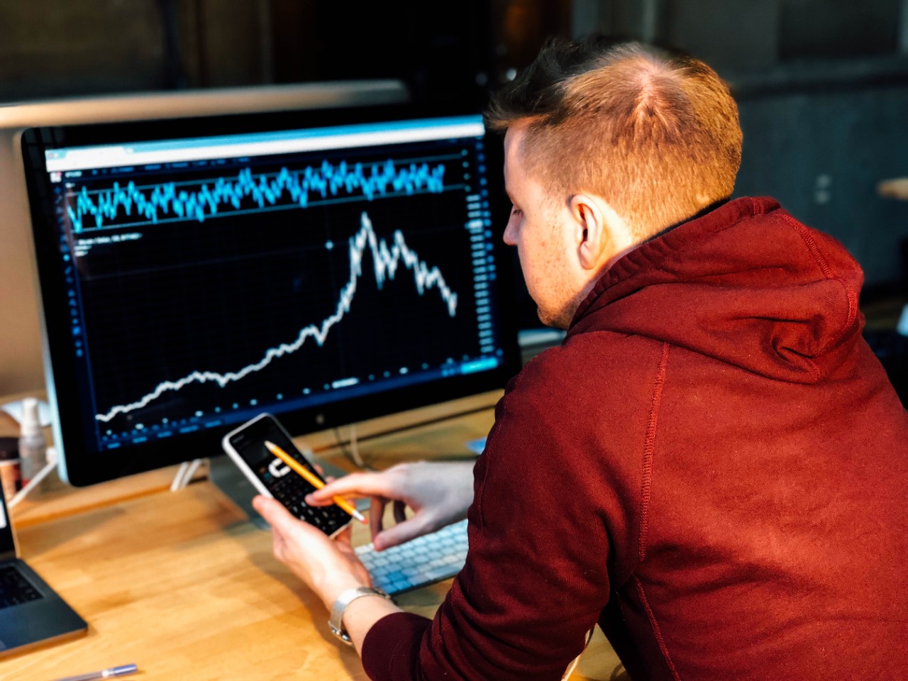 Man following market charts on computer screen as part of his job in finance