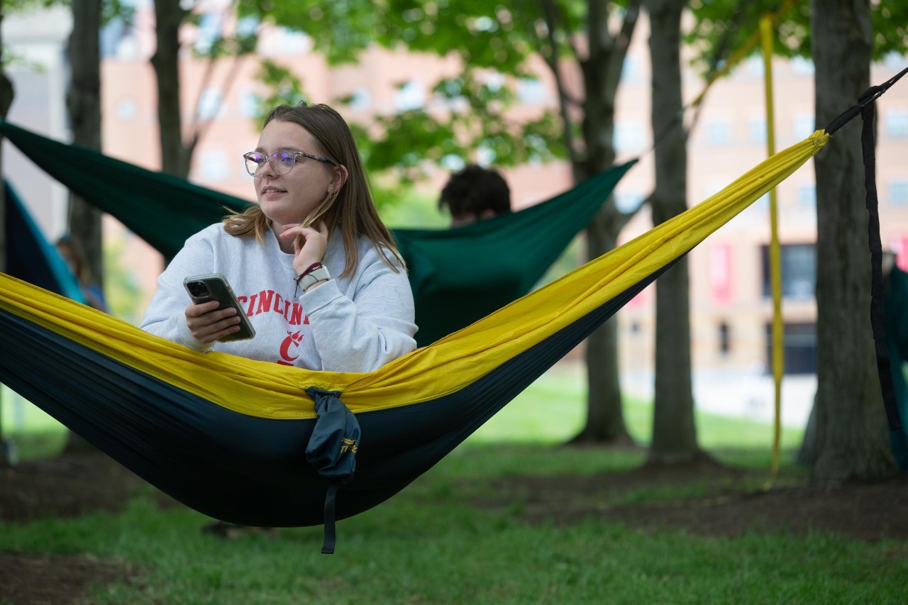 A UC student relaxing in a hammock on campus