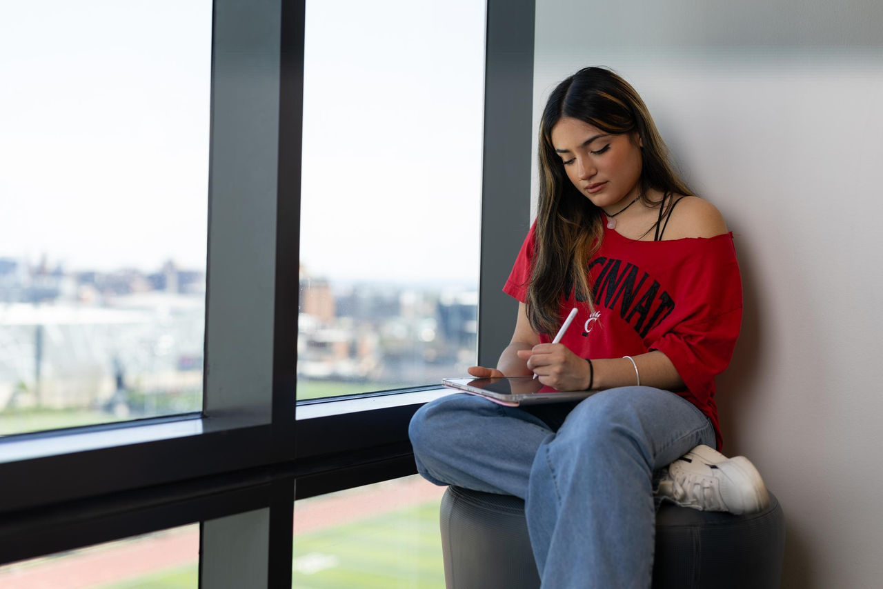 Student sitting by window using tablet, exploring how to pay for college without loans
