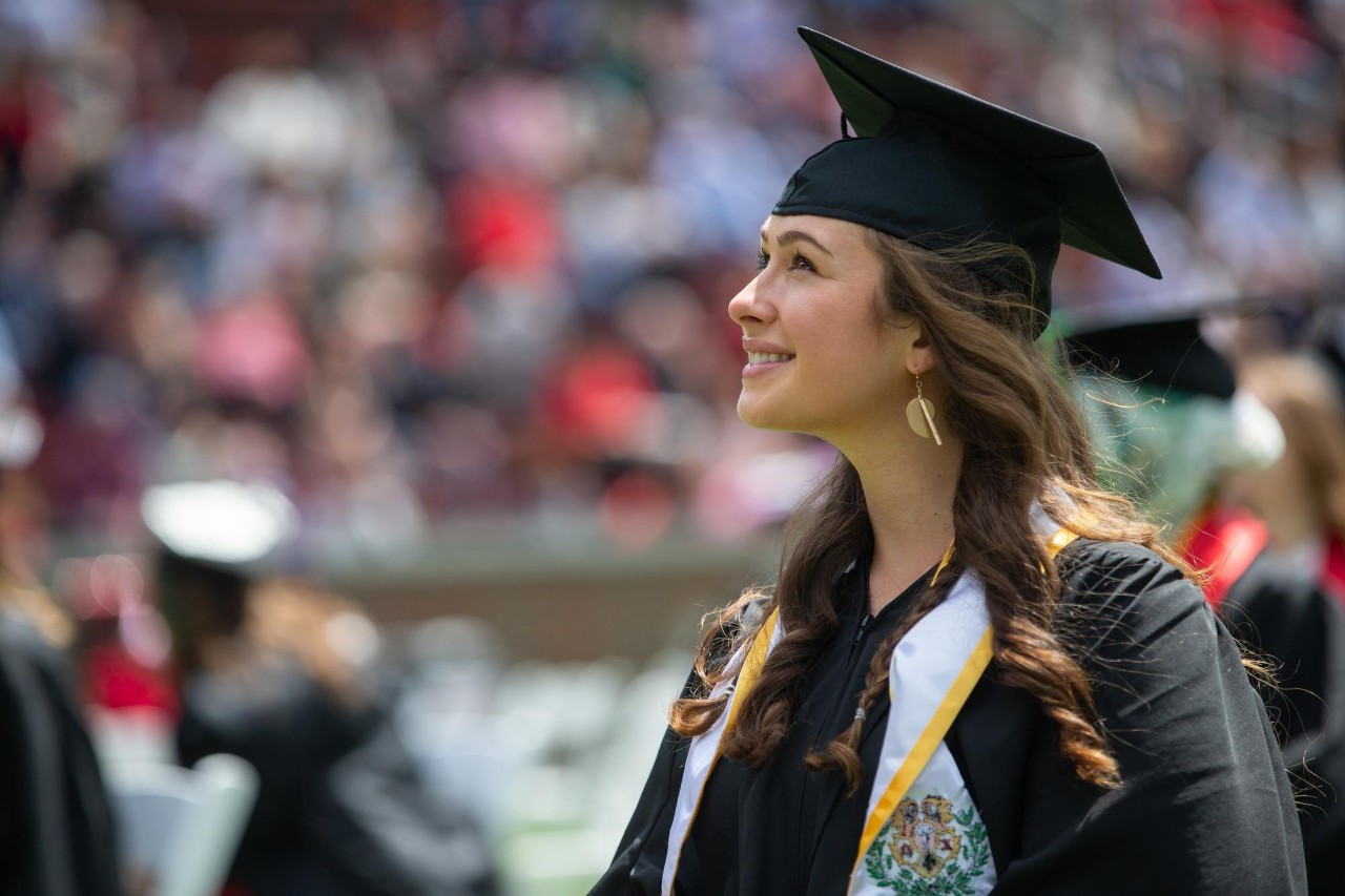 UC student at Commencement smiling up at the sky