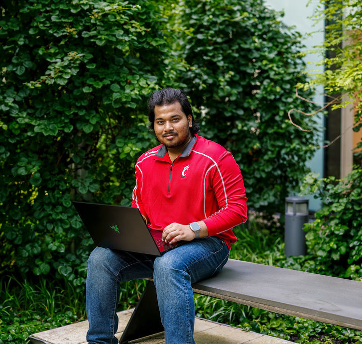 Computer Science student who co-ops with AI poses with a laptop outside