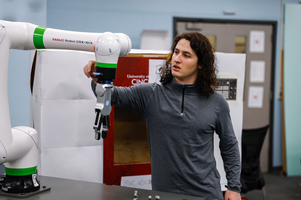 A mechanical engineering student works with a robotic arm, demonstrating a good major for an AI future