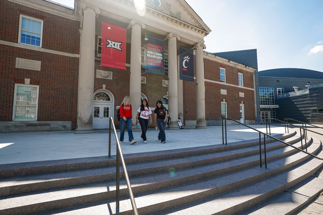 Three UC students walking in the heart of campus talking about how to know if a college is the right fit.