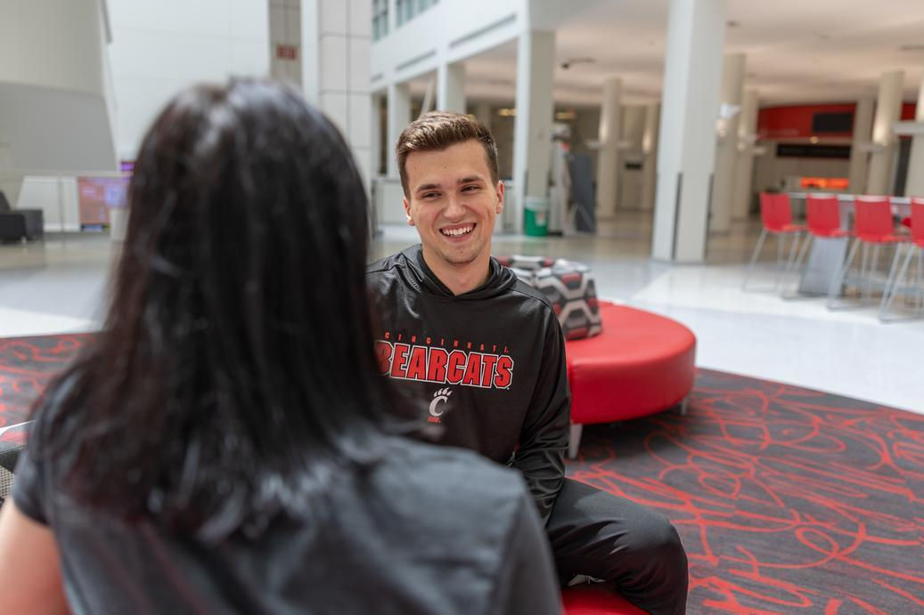 Two students sitting, talking about how to choose between two colleges