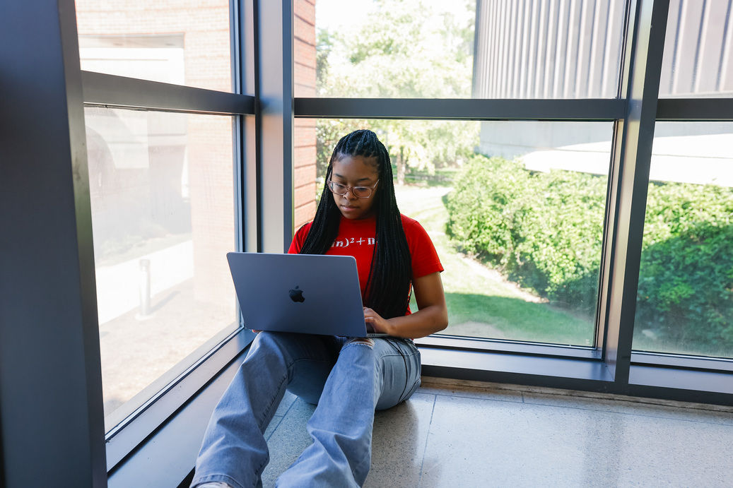 Student seated, on her laptop, looking for tips on homesickness in college