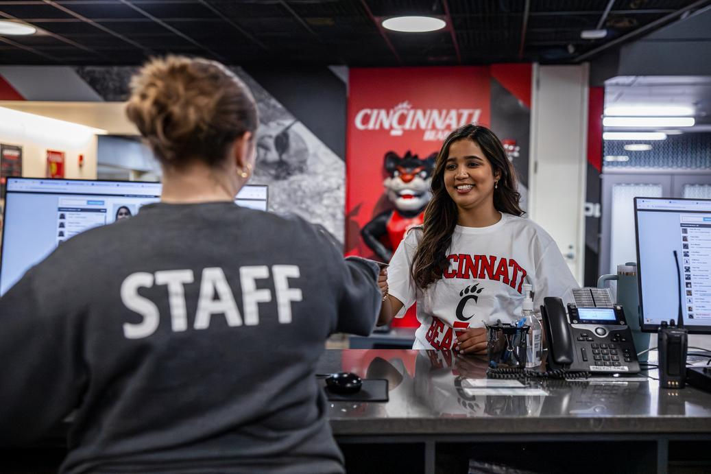 A UC Campus Rec staff member swipes in a UC student. Campus jobs like those offered at the Rec Center are a good way to balance school and work in college.