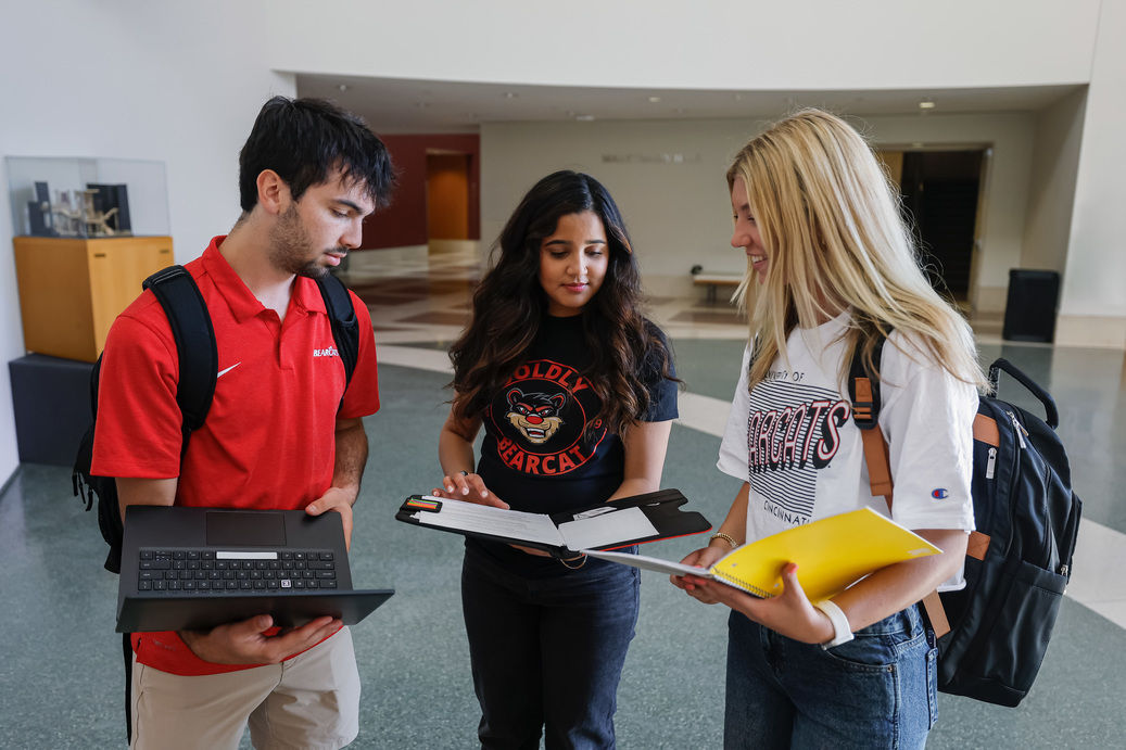 Three students stand, discussing what college really costs