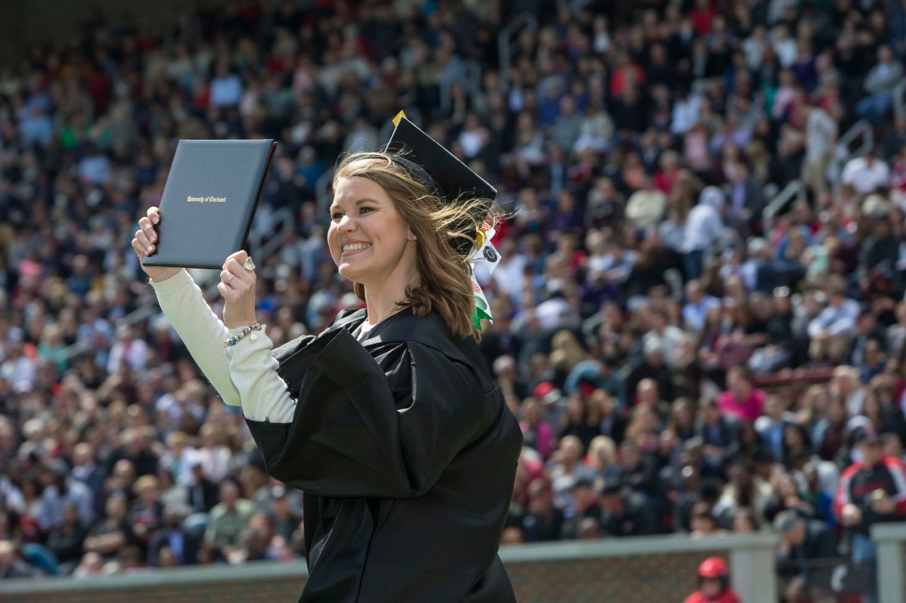 A UC student proudly shows off her diploma at Commencement 
