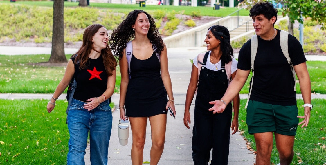 UC students talking and walking on campus together
