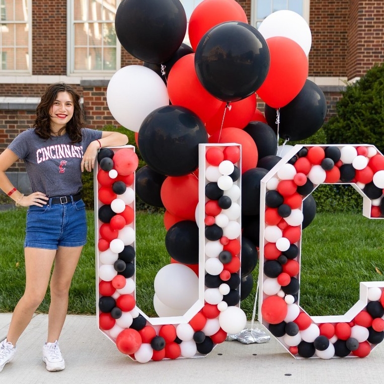 Student posing with UC made out of red, black and white balloons