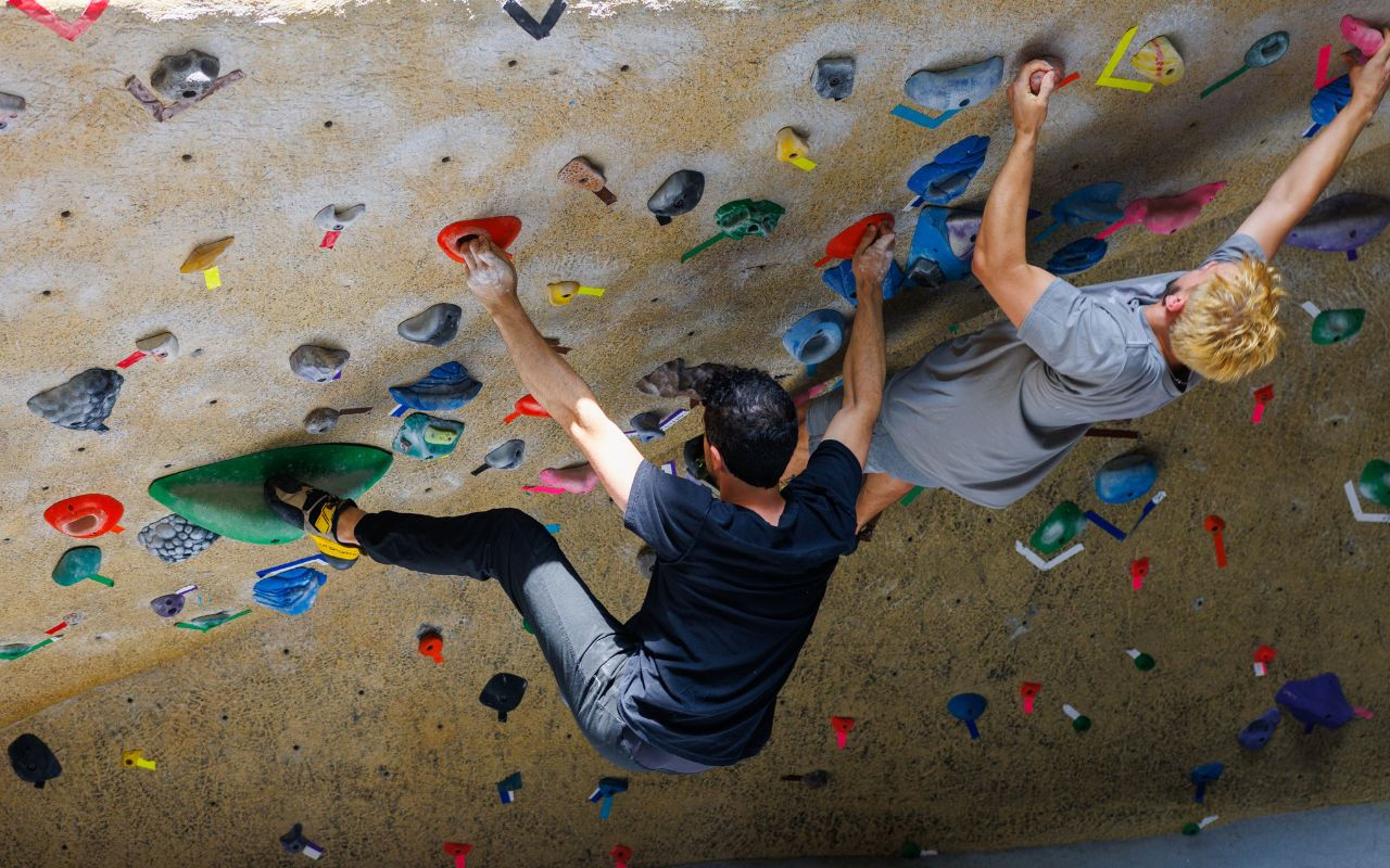 University of Cincinnati student smiles as she climbs on UC's Rec Center climbing wall