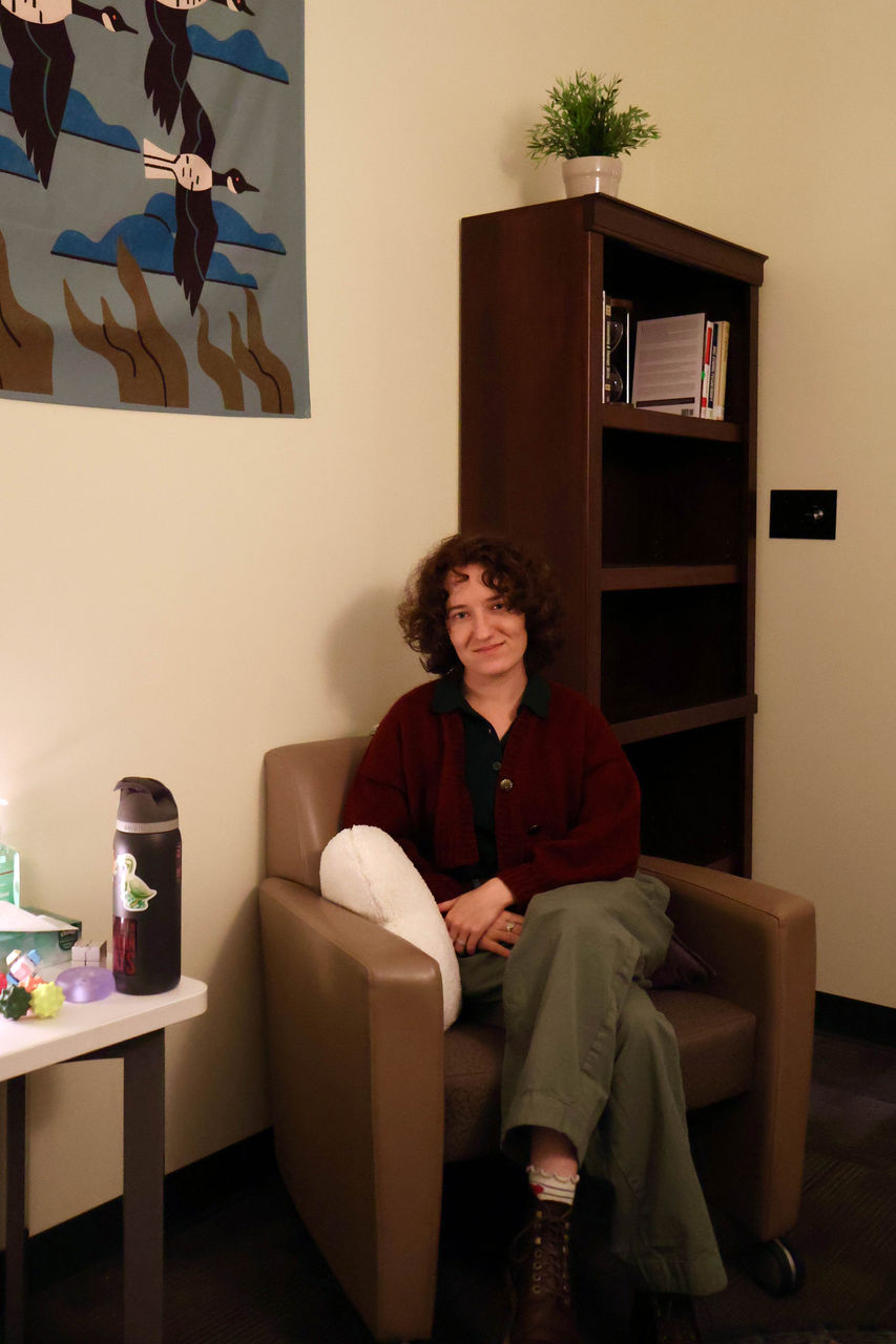 Photograph of Alice smiling inside their office. They are wearing a burgundy cardigan.
