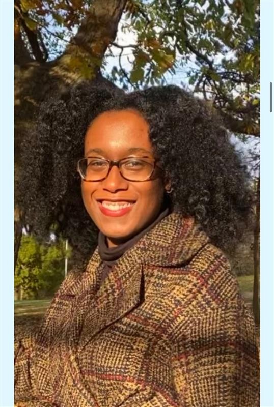 Photograph of Dylanne Twitty outside smiling in the sun. She is wearing a brown winter jacket. 