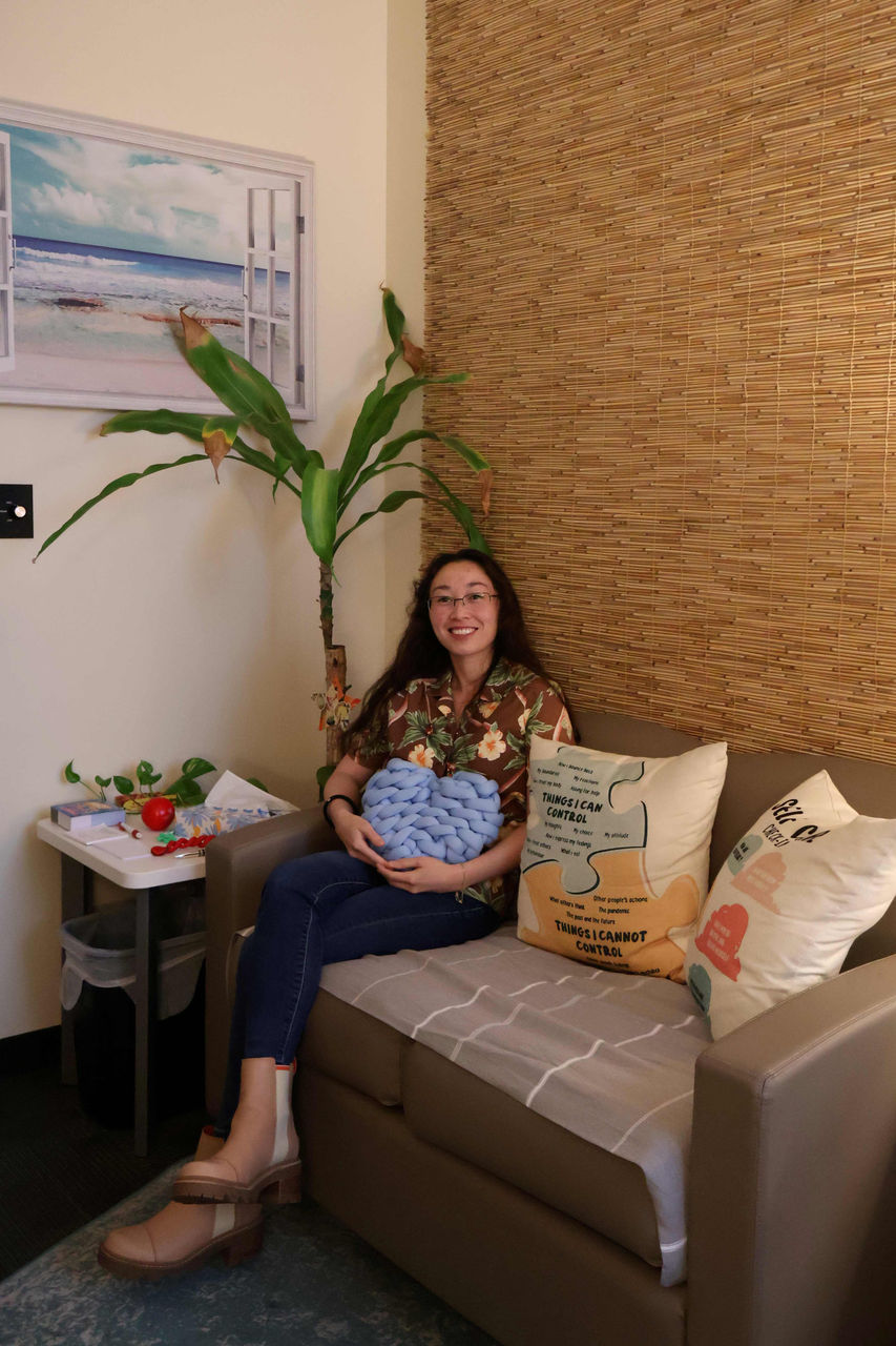 Photograph of Kea Brown smiling in her office. She is smiling and wearing glasses and a Hawaiian floral print top.