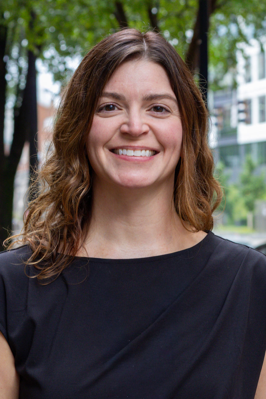 Photograph of Whitney Richardson smiling outside of CAPS building. She is wearing a black top.