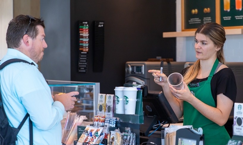 A students with a backpack stands at the Starbucks counter at Lindner College of Business.