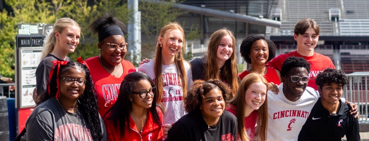 Students in UC gear smiling on main street