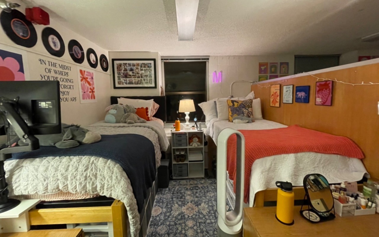 Two beds with white linens, and color blankets, decorated with graphics and record albums