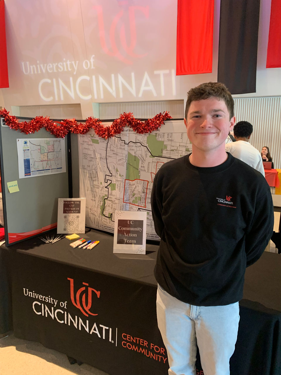 Image of a student standing in front of a table; Table contains information about Off-Campus & Commuter Student Engagement