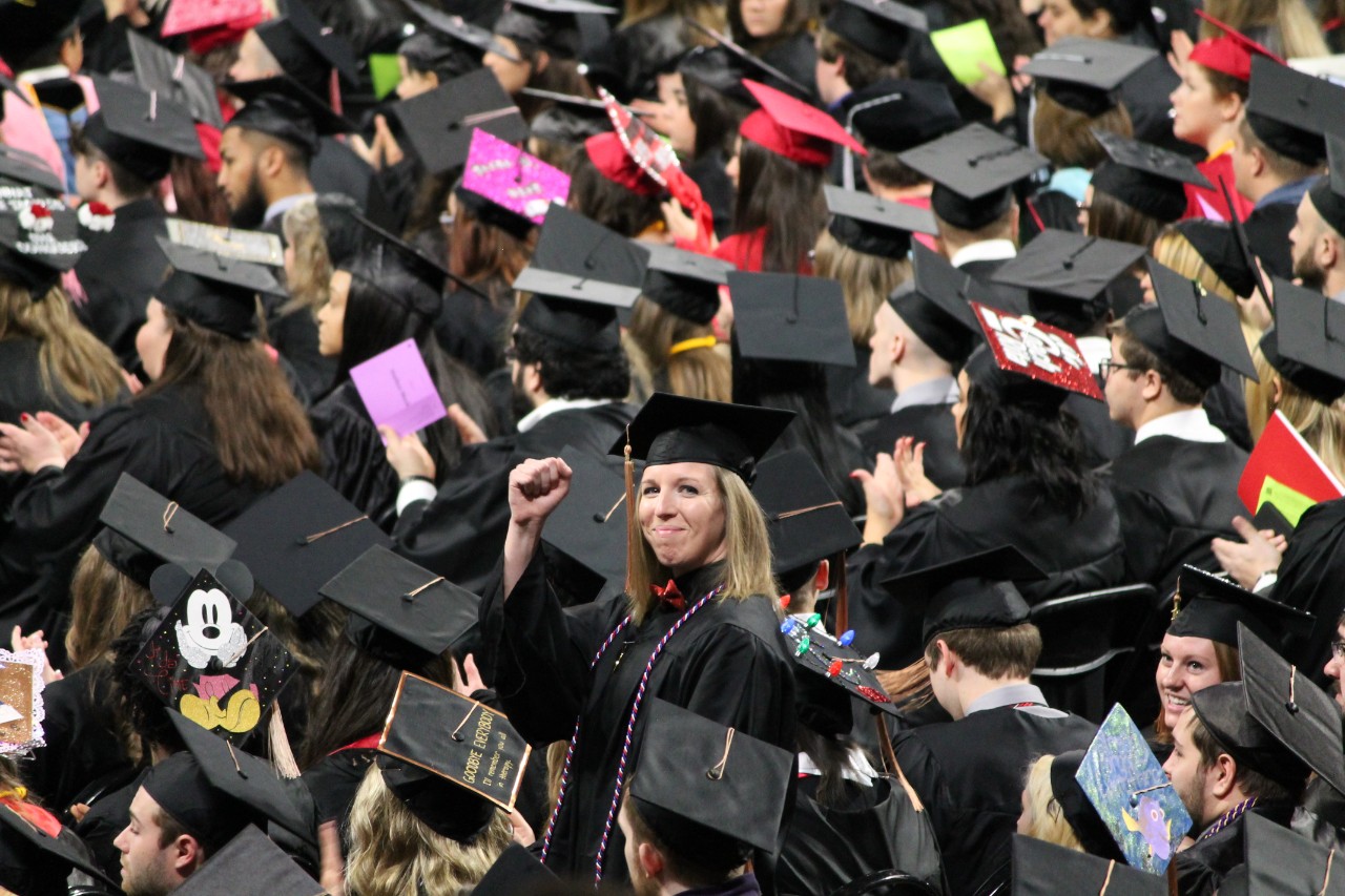 A student celebrates amid a sea of graduates